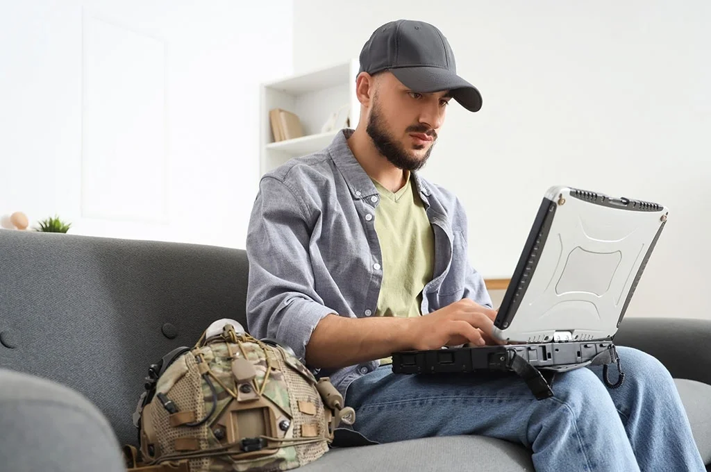 Veteran sitting on a couch looking at his laptop