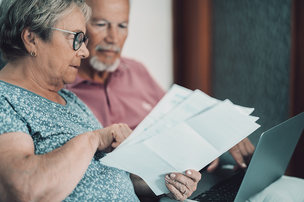 A veteran using a laptop on the couch with a household member, looking over immediate financial help options for veterans in Florida