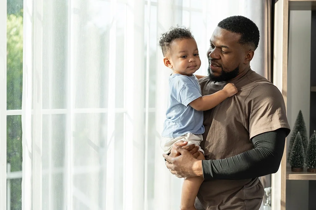 A father holds his child in the living room