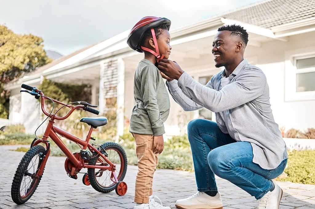 A veteran helps his son get ready to ride a bike